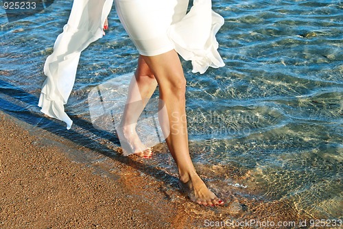 Image of Woman in white dress walking on beach