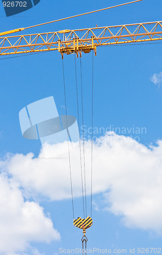 Image of Crane hook over blue sky with clouds