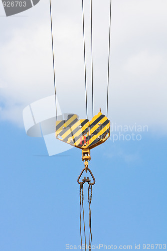 Image of Crane hook over blue sky with clouds