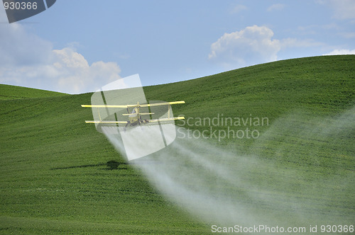 Image of Biplane Crop Duster spraying a farm field.