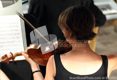 Image of woman playing on violin in orchestra