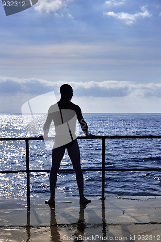 Image of Silhouette of young man standing at the seaside