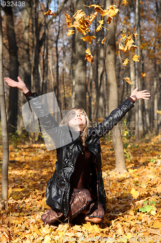 Image of beautiful girl throwing up autumn leaves