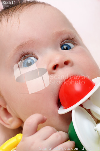 Image of baby girl biting rattle