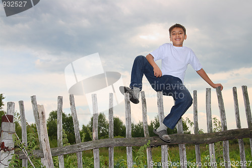 Image of happy boy sitting on fence