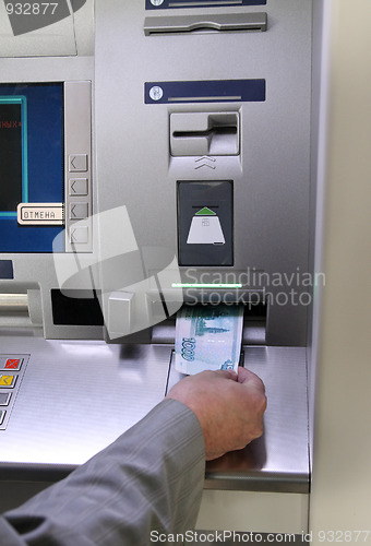 Image of hand inserting banknote into cash dispense