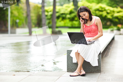 Image of Woman on the phone and working on her laptop