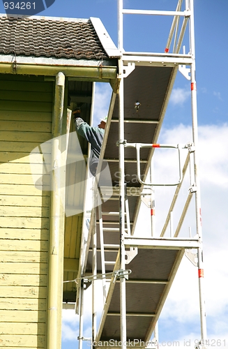 Image of Man painting a house