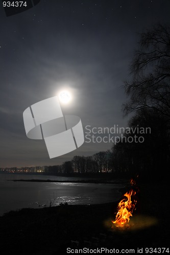 Image of bonfire flame and moon over lake