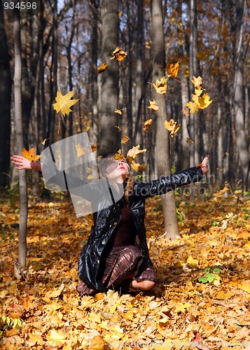 Image of beautiful girl throwing up autumn leaves