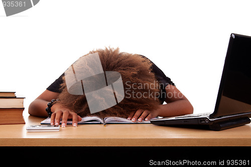 Image of Stressed young black woman,  sitting at a table among books and laptop 