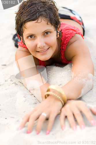 Image of brunet woman in red lying on a sand