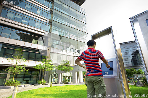 Image of asia boy play the touch screen in modern building outside