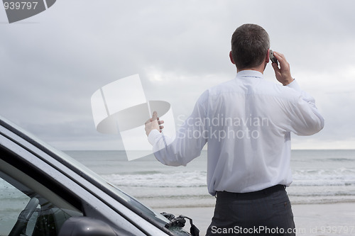 Image of Businessman talking on cell phone at the sea