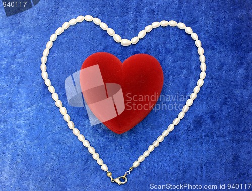 Image of red heart and pearly neacklace on blue velvet