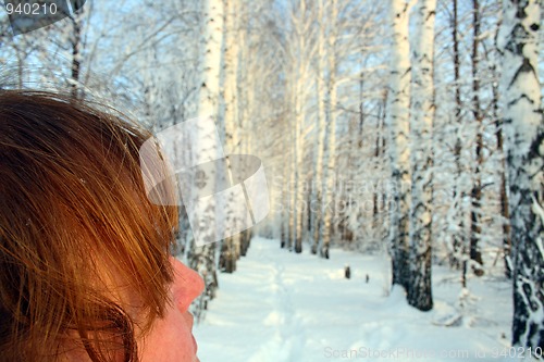 Image of woman with red hair, looking on winter wood