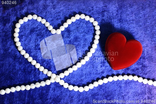 Image of red heart and pearly neacklace on blue velvet