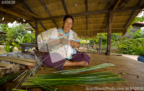 Image of asian woman making straw mats