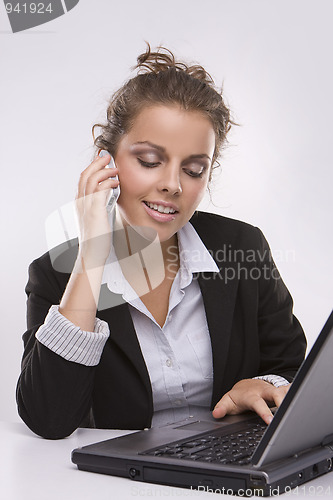 Image of woman using a laptop computer and talking on the phone