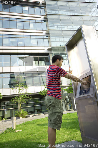 Image of asia man touch the screen at moder building outside