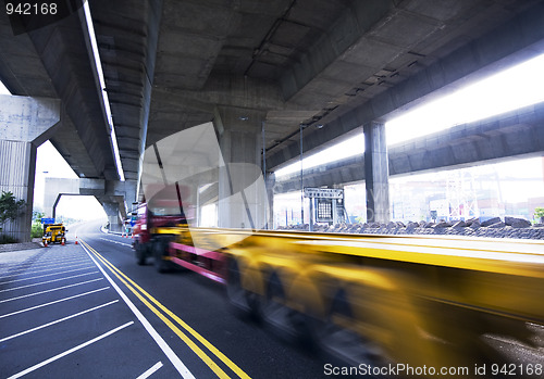 Image of container car fast moving under the freeway bridge