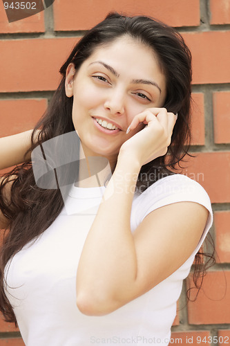 Image of Young smiling woman at wall talking cellphone