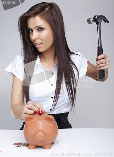 Image of  Young woman breaking a piggy bank