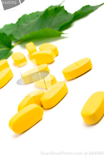 Image of yellow vitamin pills over green leaves