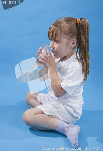 Image of Small cute girl is drinking water on blue background