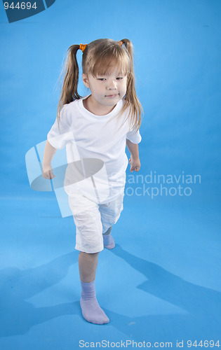 Image of Small serious girl is posing as fighter isolated on blue