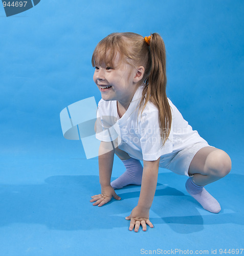 Image of Small girl is posing as frog on blue