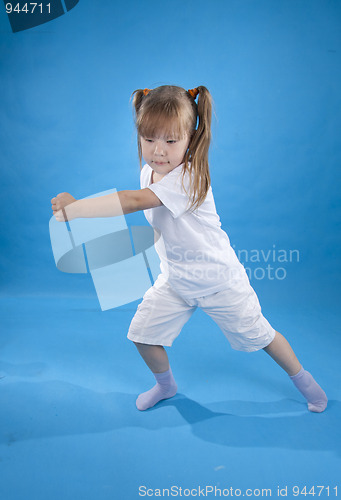 Image of Small serious girl is posing as fighter isolated on blue