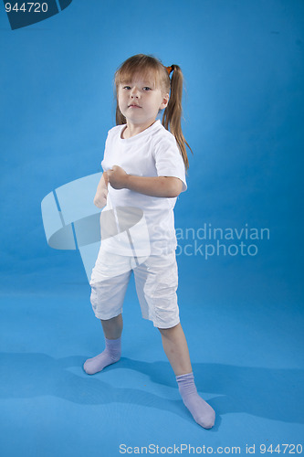 Image of Small serious girl is posing as fighter isolated on blue