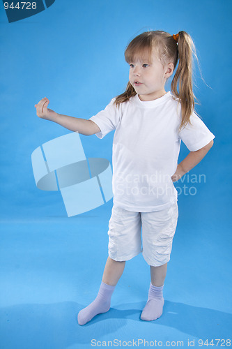 Image of Small serious girl is posing isolated on blue