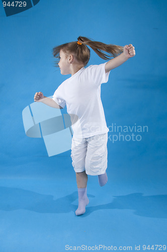 Image of Small serious girl is jumping isolated on blue