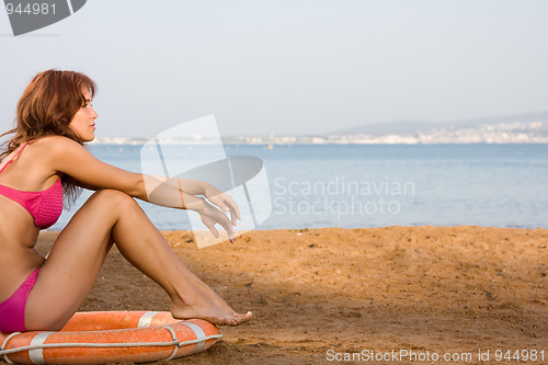 Image of A young girl sits on a lifebuoy on the beach