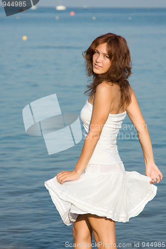 Image of Young beautiful woman in a white dress against a background of t