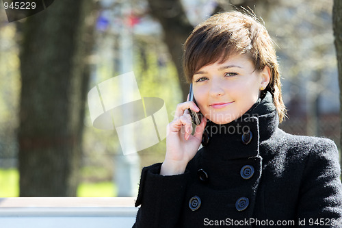 Image of Cute woman in park with cellphone