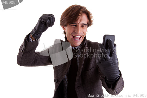 Image of Portrait of a young happy businessman looking to the phone, in autumn/winter clothes