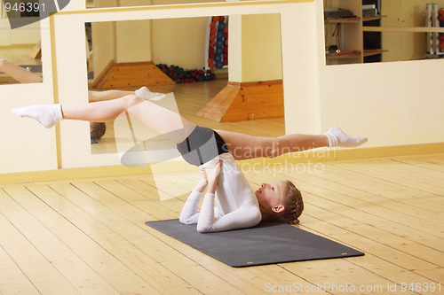 Image of Little gymnast making exercises in gym