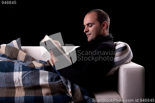 Image of man lying on the sofa reading a book