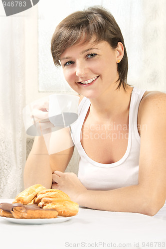 Image of Smiling cute woman drinking tea with cakes