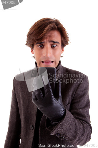 Image of Portrait of a young unhappy businessman looking to the phone, in autumn/winter clothes