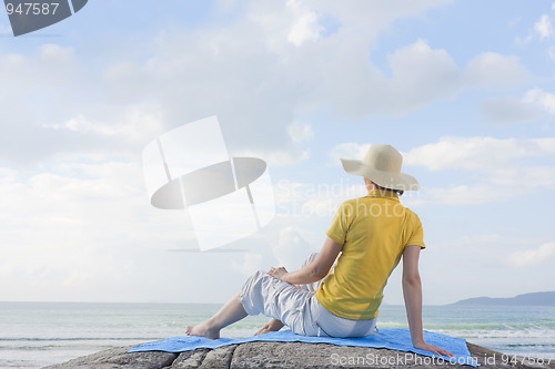 Image of Woman sitting on a rock at the sea