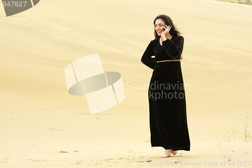 Image of Woman walking by desert calling on cellphone