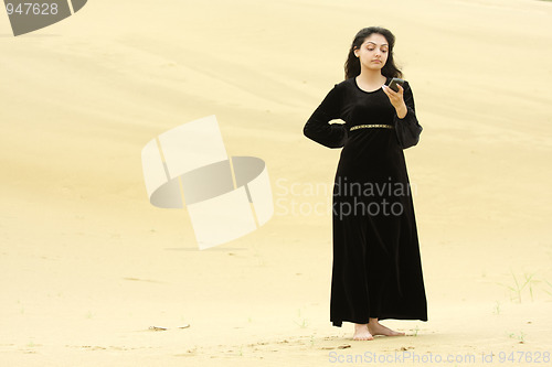 Image of Woman in desert messaging on cellphone