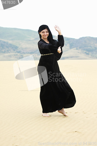 Image of Young smiling woman dancing in desert