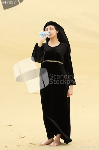 Image of Woman in desert drinking water from bottle