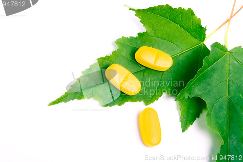 Image of yellow vitamin pills over green leaves