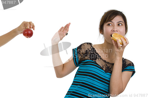 Image of woman with hamburger refusing an apple